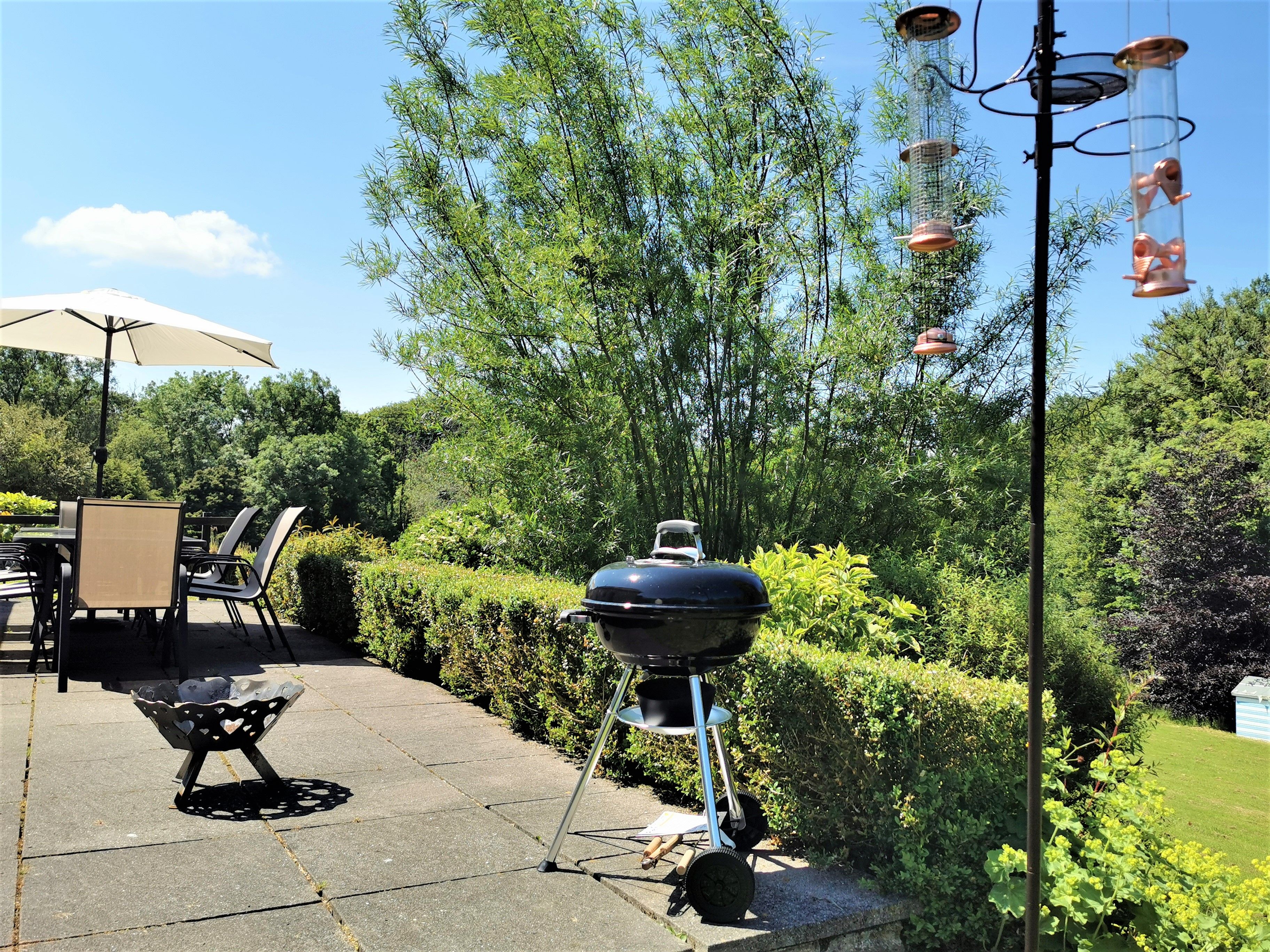 Un patio al aire libre con una parrilla, una mesa con sillas y una lámpara colgante.