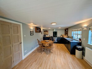 Una cocina compacta con comedor, armarios de madera y estufa integrada.