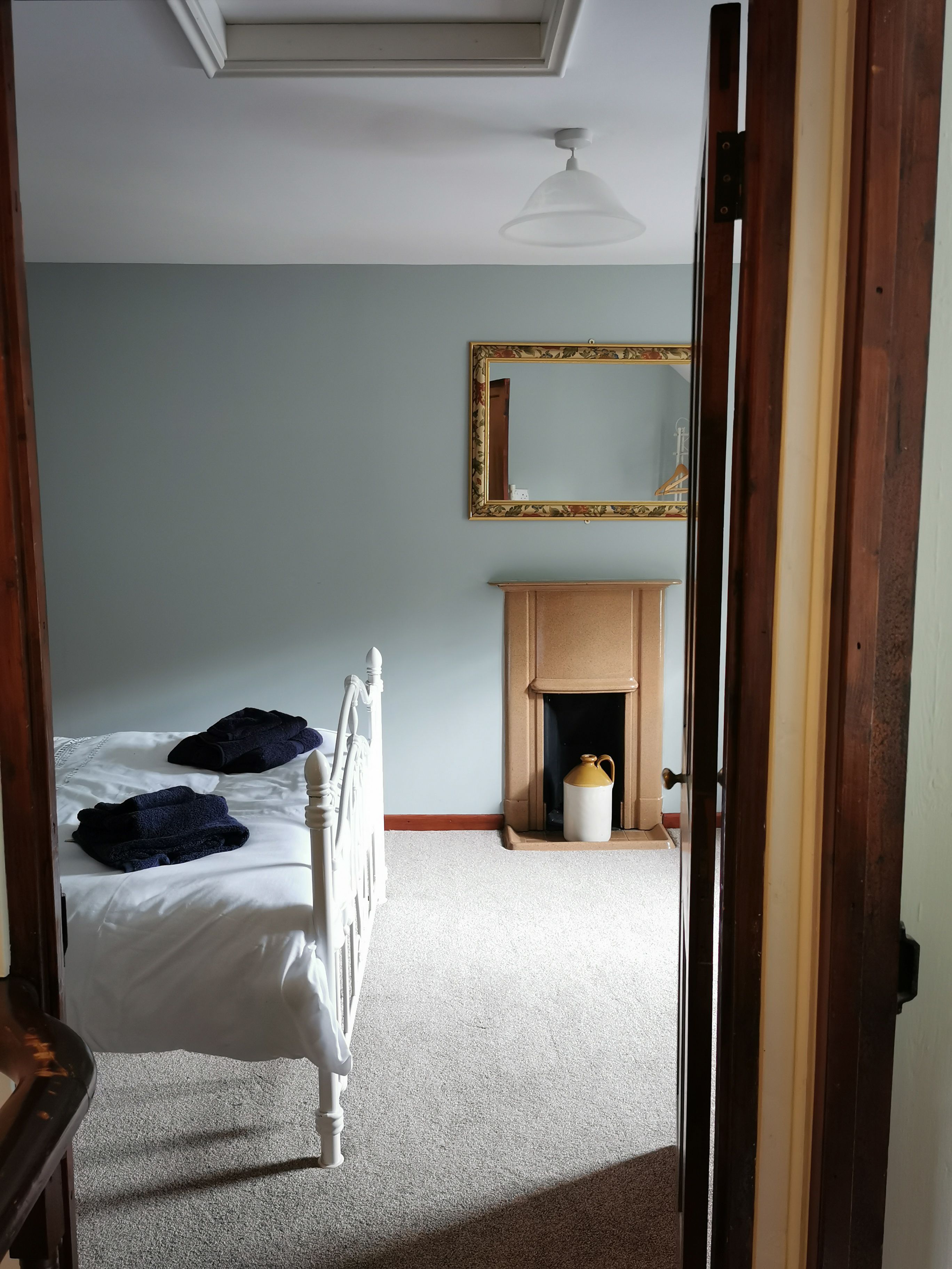 Un dormitorio con cama, chimenea y espejo.