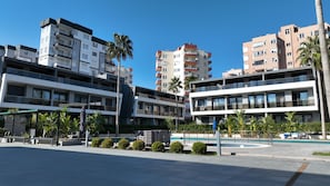 A modern hotel with multiple floors, balconies, and a pool area.