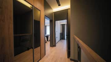 A modern hotel corridor with wooden flooring, glass partitions, and a neutral color scheme.