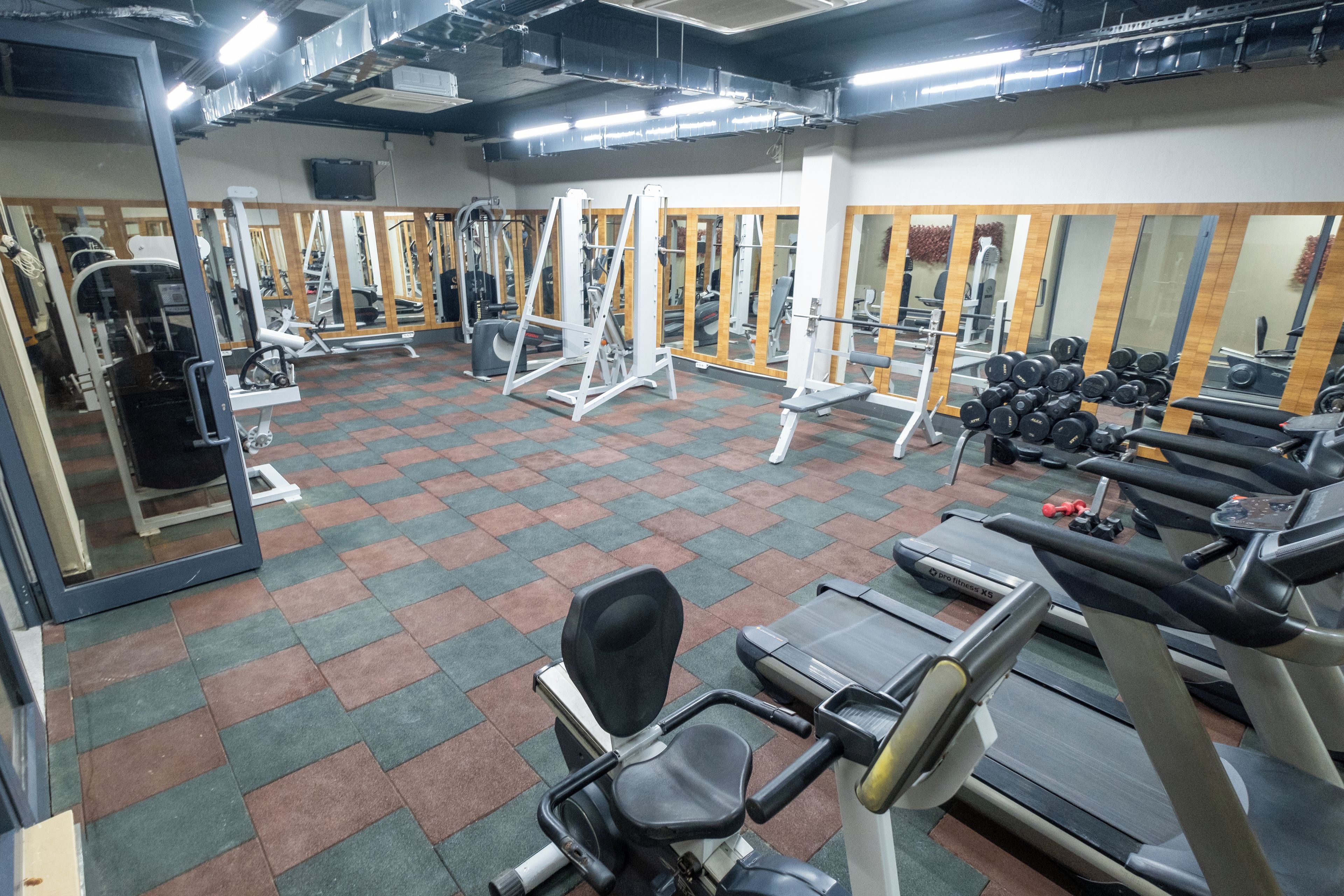 A gym with various exercise equipment, including treadmills, weight machines, and free weights.