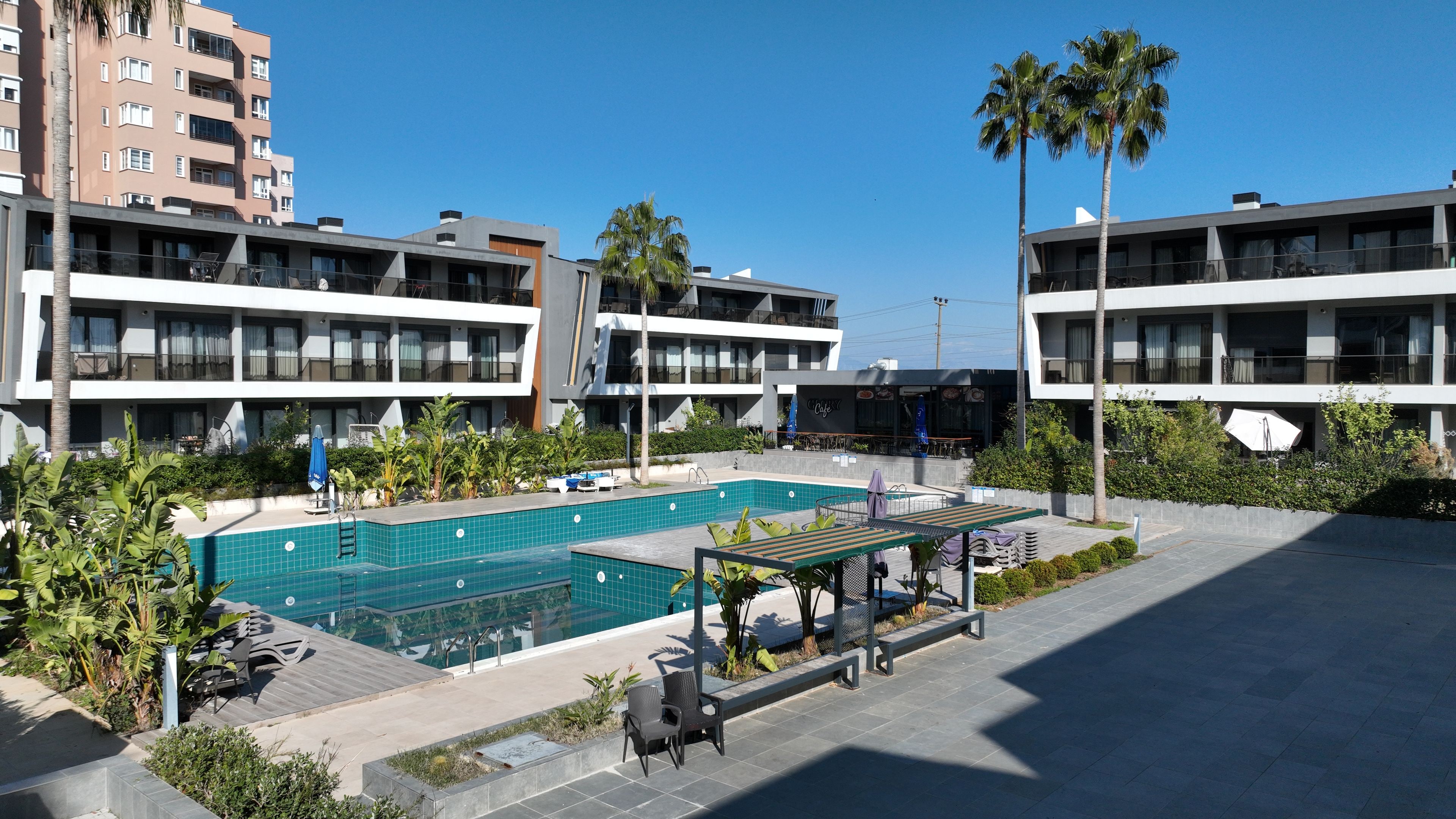 Un hôtel moderne doté d’une piscine, d’un espace extérieur aménagé et d’un café.