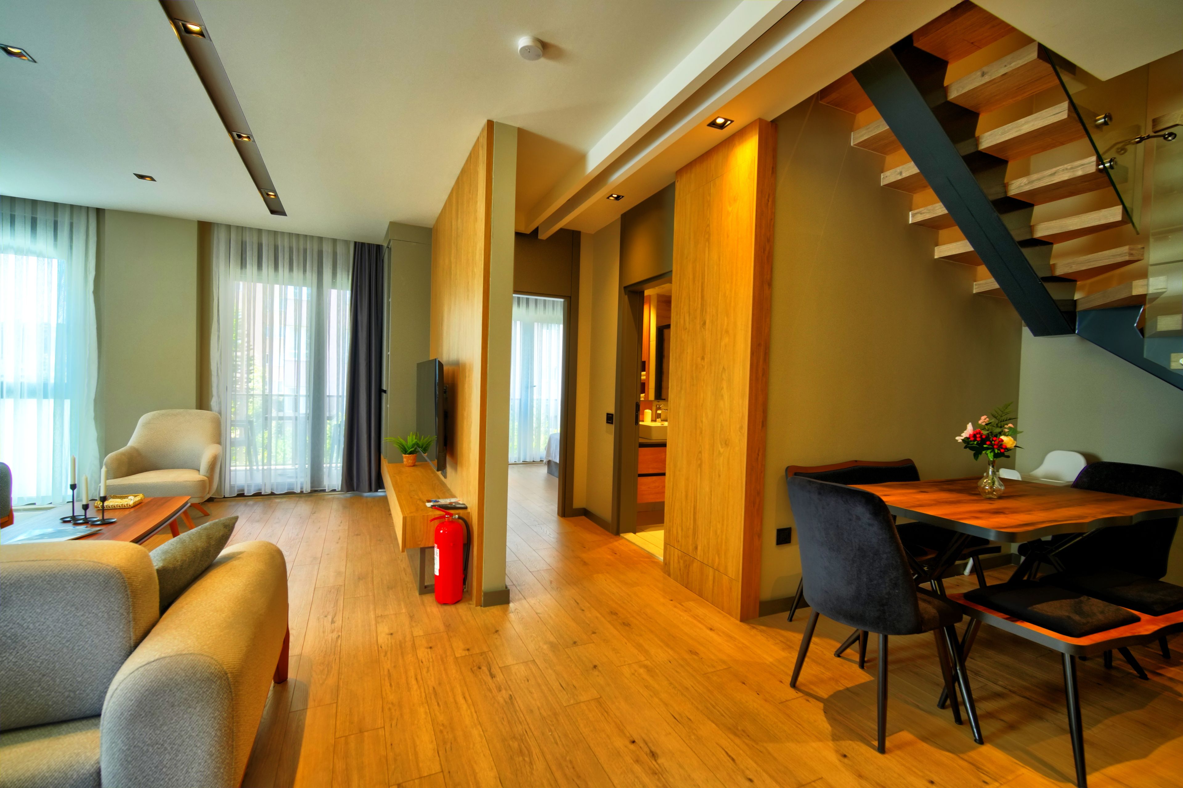 A modern living room with a wooden floor, a sofa, a coffee table, and a dining area with a wooden table and chairs.