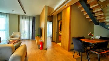 A modern living room with a wooden floor, a sofa, a coffee table, and a dining area with a wooden table and chairs.