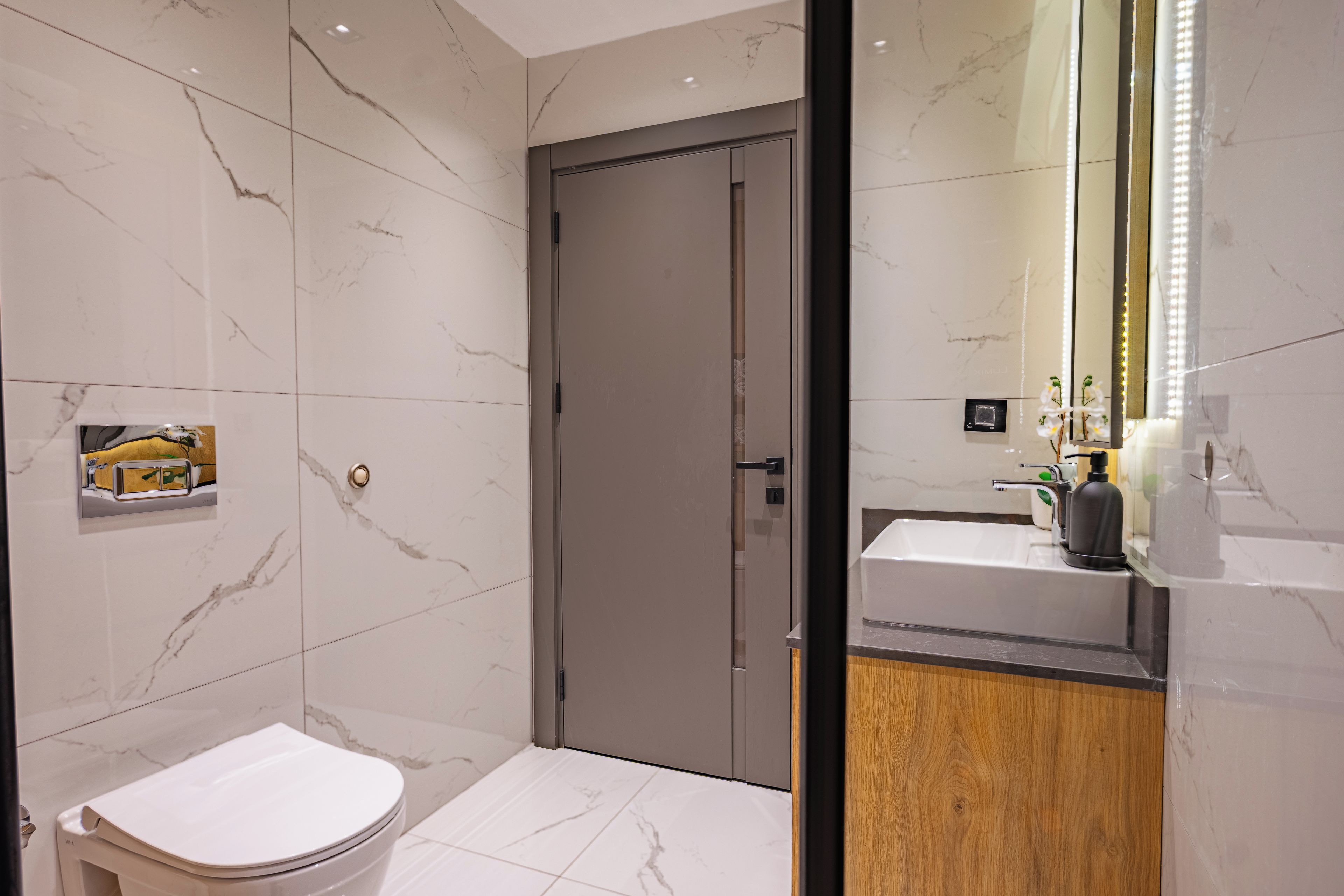 A modern bathroom with a toilet, a sink, and a mirror.