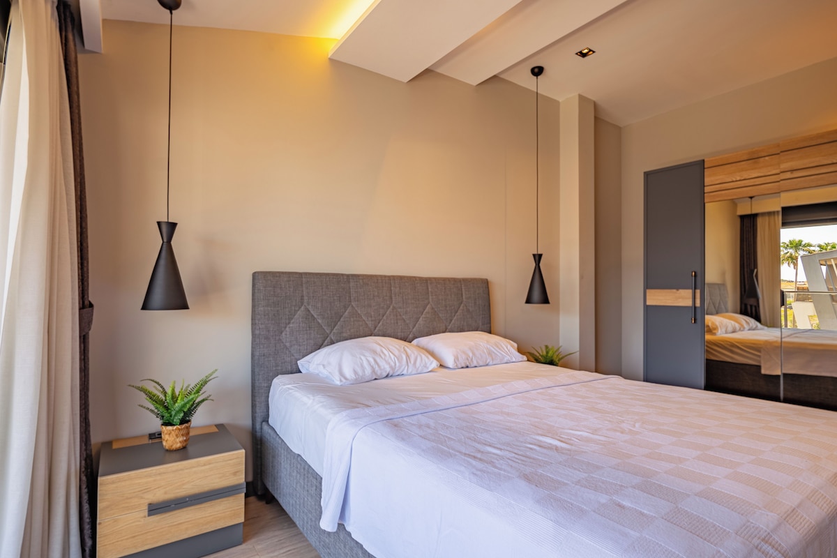 A modern bedroom with a large bed, bedside tables, and pendant lighting.