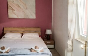 A bedroom with a wooden headboard, two beds, a bedside table with a lamp, and a window with curtains. - 1 bedroom stunning apartment in Cres (Cres)