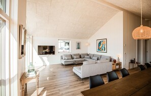 A spacious living area with a large sectional sofa, a dining table with chairs, and a television mounted on the wall. - Awesome home in Ebeltoft with sauna (Ebeltoft)