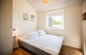 Ein Schlafzimmer mit einem Bett, einem Fenster und einer Wandleuchte.