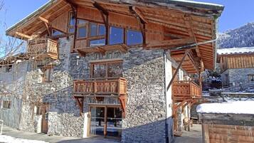 A multi-story wooden building with stone walls, balconies, and large windows.