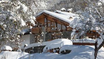 A snow-covered lodge with a stone facade and wooden balconies.