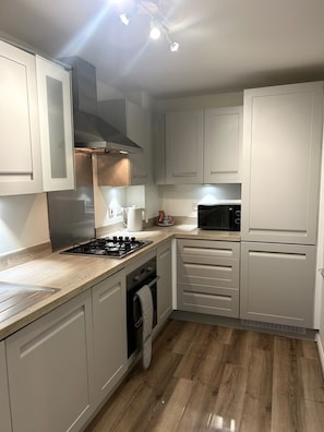Eine moderne Küche mit weißen Schränken, einem Gasherd, einer Mikrowelle und einem Backofen.