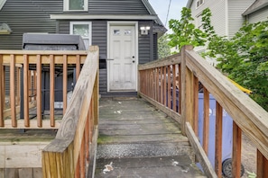 Een houten terras dat leidt naar een huis met een witte deur en een garage.