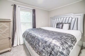Een slaapkamer met een bed, een dressoir en een raam met gordijnen.