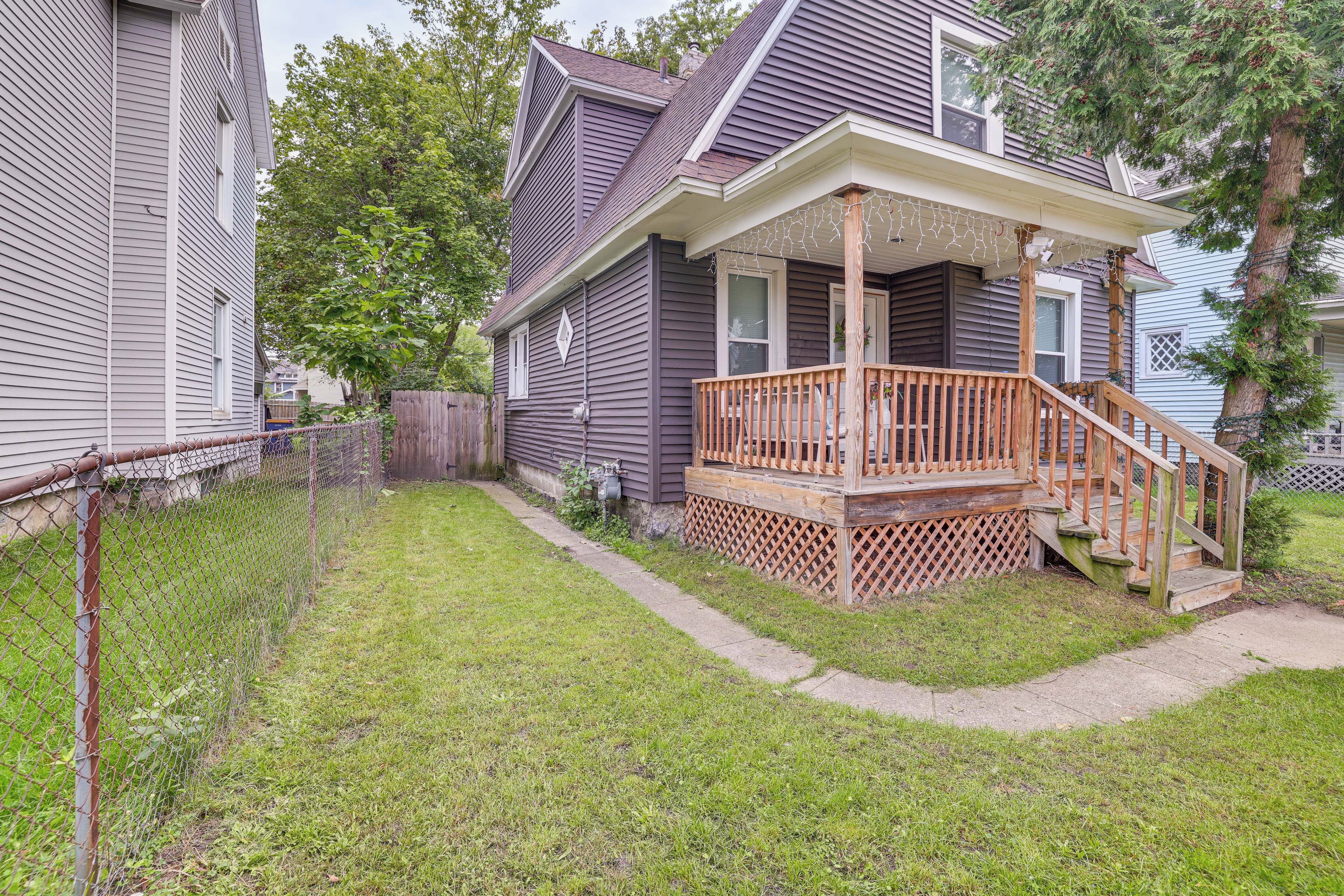 A residential house with a front porch, a wooden deck, and a fenced yard.