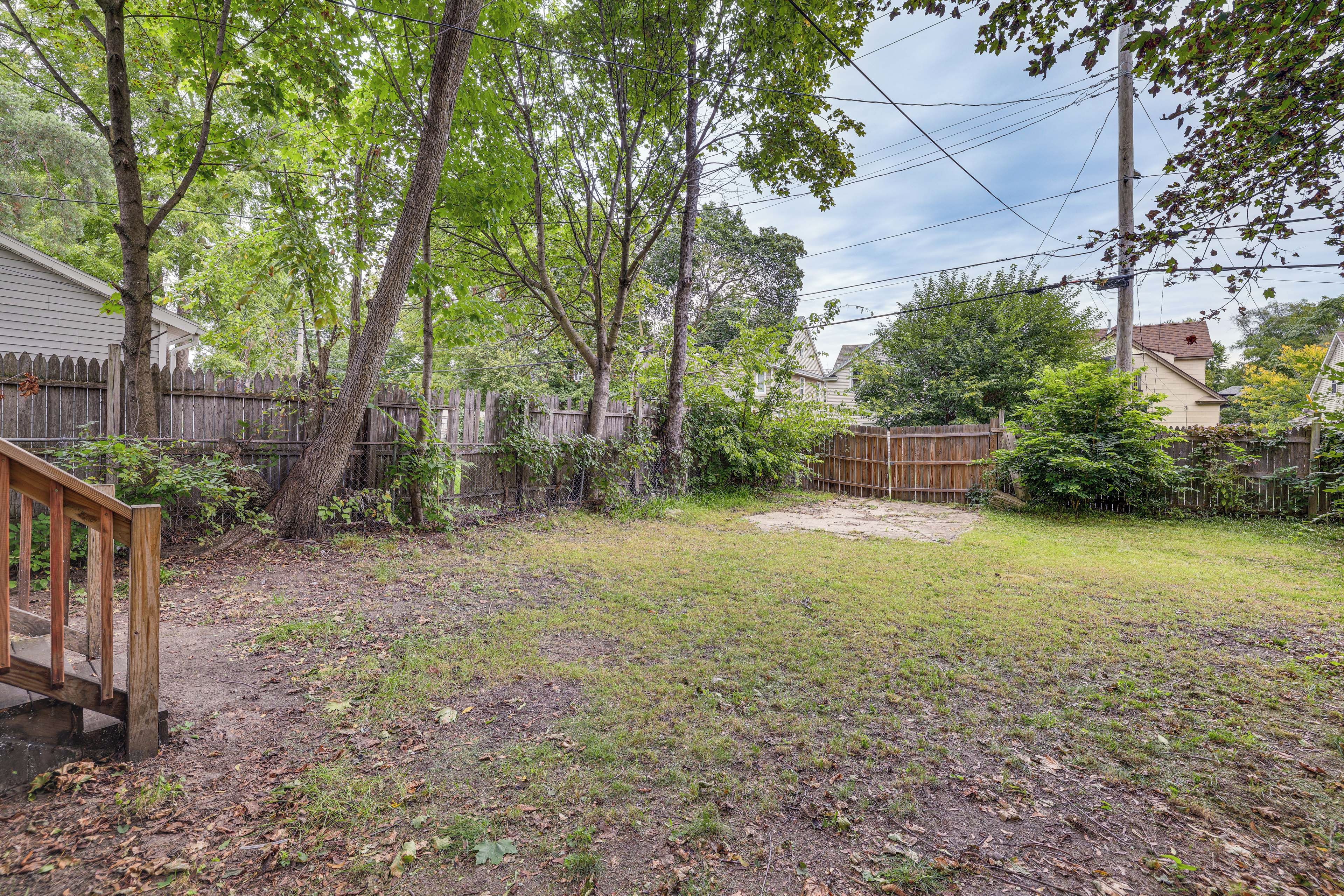 A backyard with a wooden deck, a fenced area, and a grassy lawn.