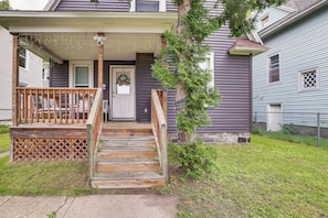 A residential house with a wooden front porch, a door with a wreath, and a small garden area.