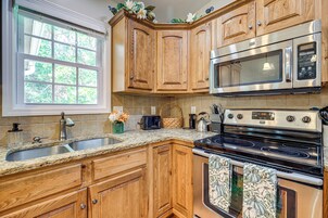 Una cocina con armarios de madera, una estufa de acero inoxidable, un microondas y un lavamanos.