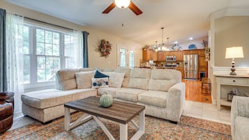 A spacious living room with a sectional sofa, a coffee table, and a view of the kitchen in the background.