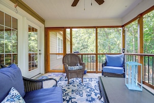 A covered porch with a seating area, including a chair and a sofa, and a table.