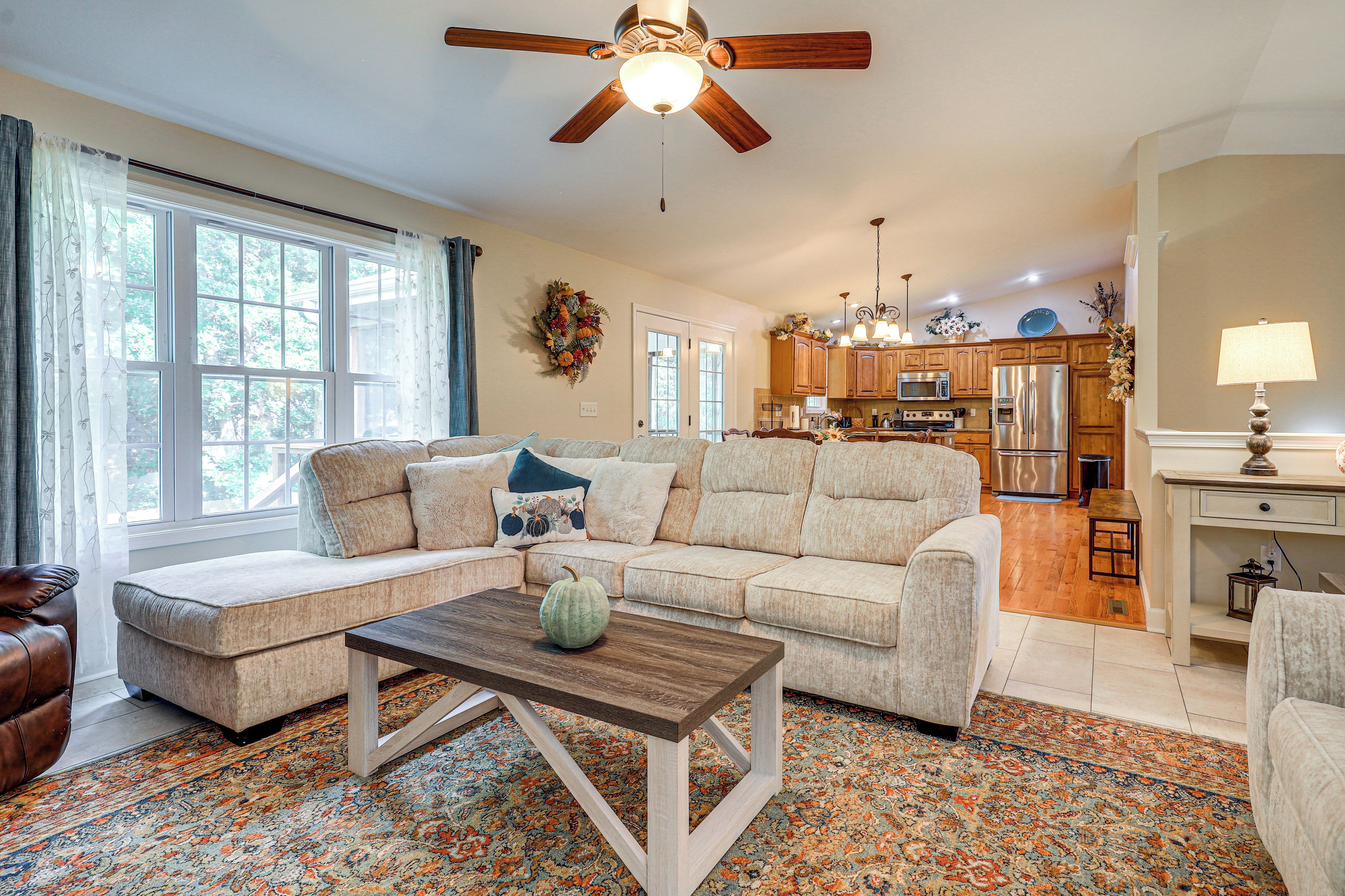 A spacious living room with a sectional sofa, a coffee table, and a view of the kitchen in the background.