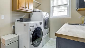 Zona de lavandería con lavadora, secadora y un mueble pequeño.
