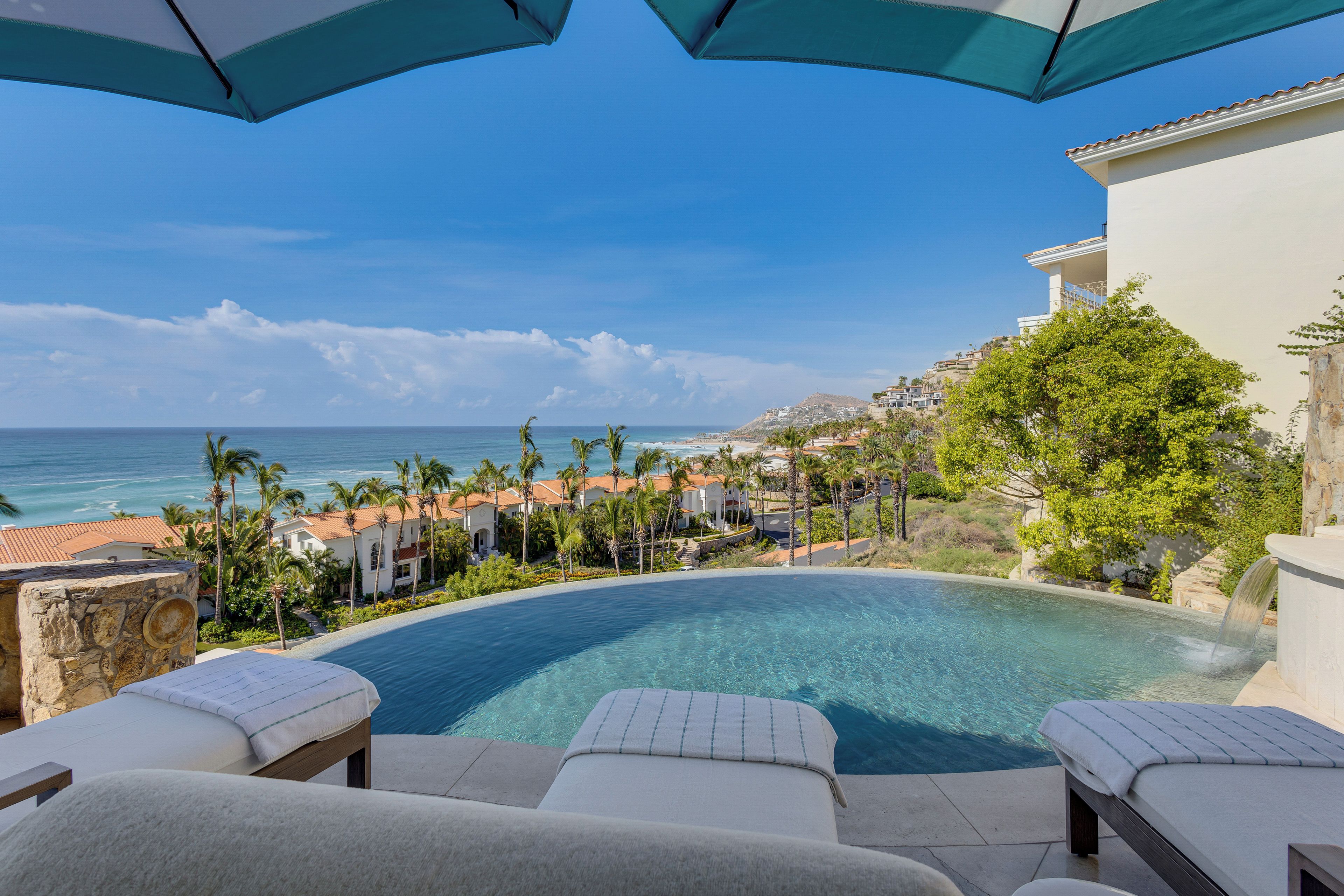 Un espace aménagé au bord de la piscine, avec des chaises longues et une vue sur l’océan.