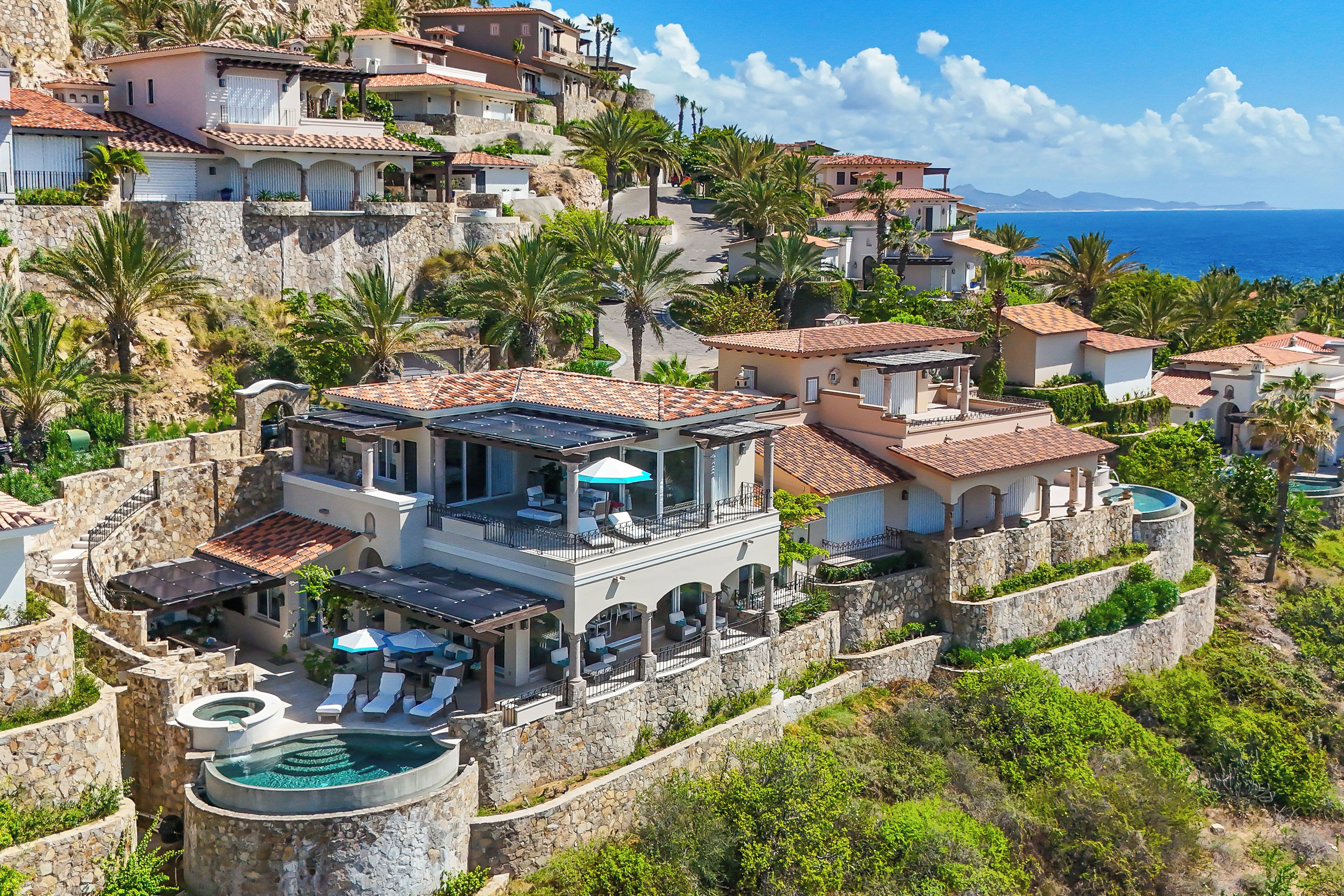 A coastal villa with a pool, multiple balconies, and a view of the sea.
