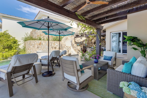 Un patio al aire libre con asientos, una mesa y una pérgola.