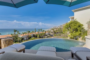 Un espace aménagé au bord de la piscine, avec des chaises longues et une vue sur l’océan.