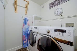 A laundry room with a front-loading washing machine, a wall-mounted clock, and a wooden drying rack. - Private Sauna at Family-friendly Eagle Home W/deck (Eagle)
