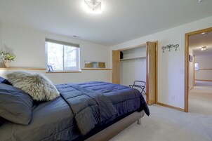 Ein Schlafzimmer mit Bett, Fenster, Kleiderschrank und einer Tür zu einem anderen Raum.