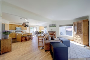 A spacious living area with a kitchen, wooden flooring, and a large window. - Private Sauna at Family-friendly Eagle Home W/deck (Eagle)