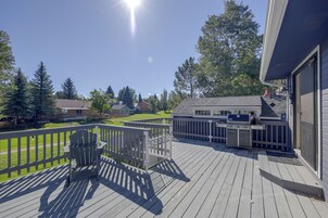 Una terraza con parrilla y mobiliario exterior, con vista a una zona residencial con casas y árboles.