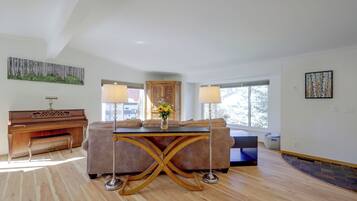 A spacious living room with a piano, a sofa, a coffee table, and a large window.