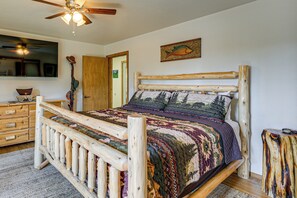 A wooden bed with a colorful quilt, a wooden headboard, and a ceiling fan. - Ski, Soak & Play at Littlefoot Cabin w/ Game Room (Pagosa Springs)