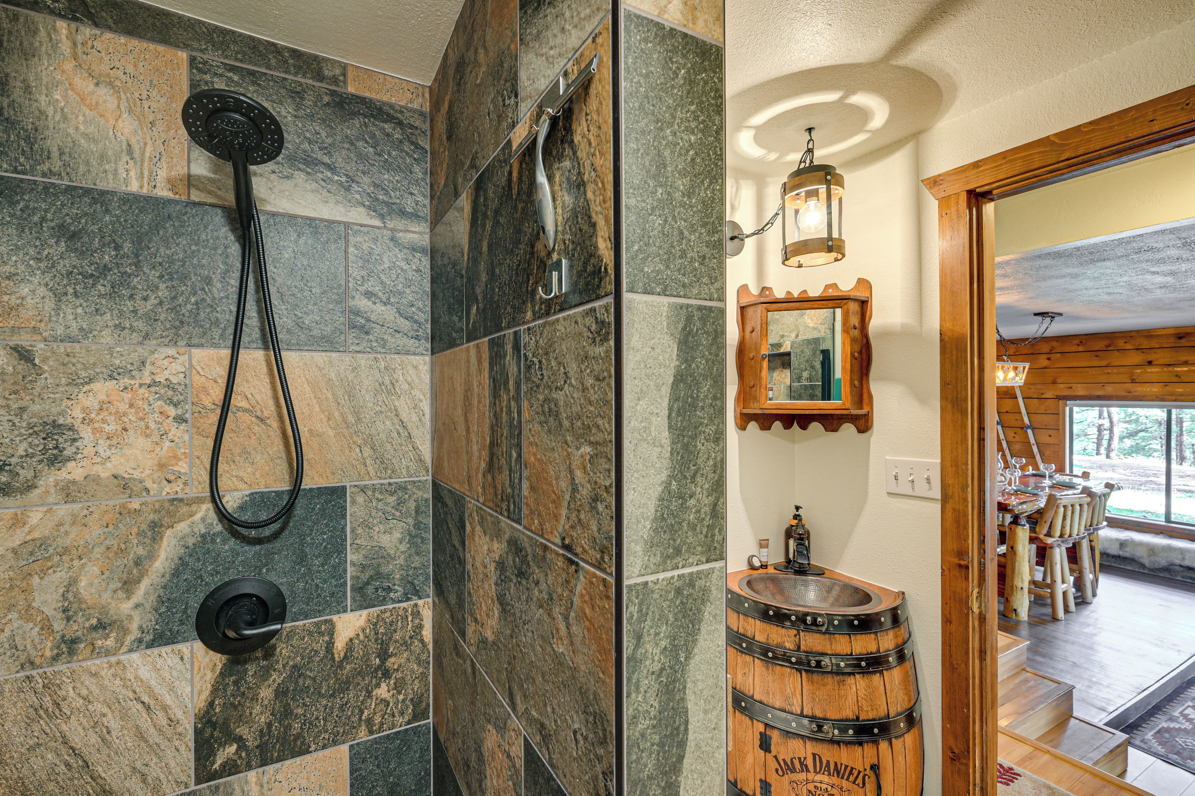 Une salle de bain avec une douche, un lavabo surmonté d’un tonneau en bois et un miroir encadré en bois.