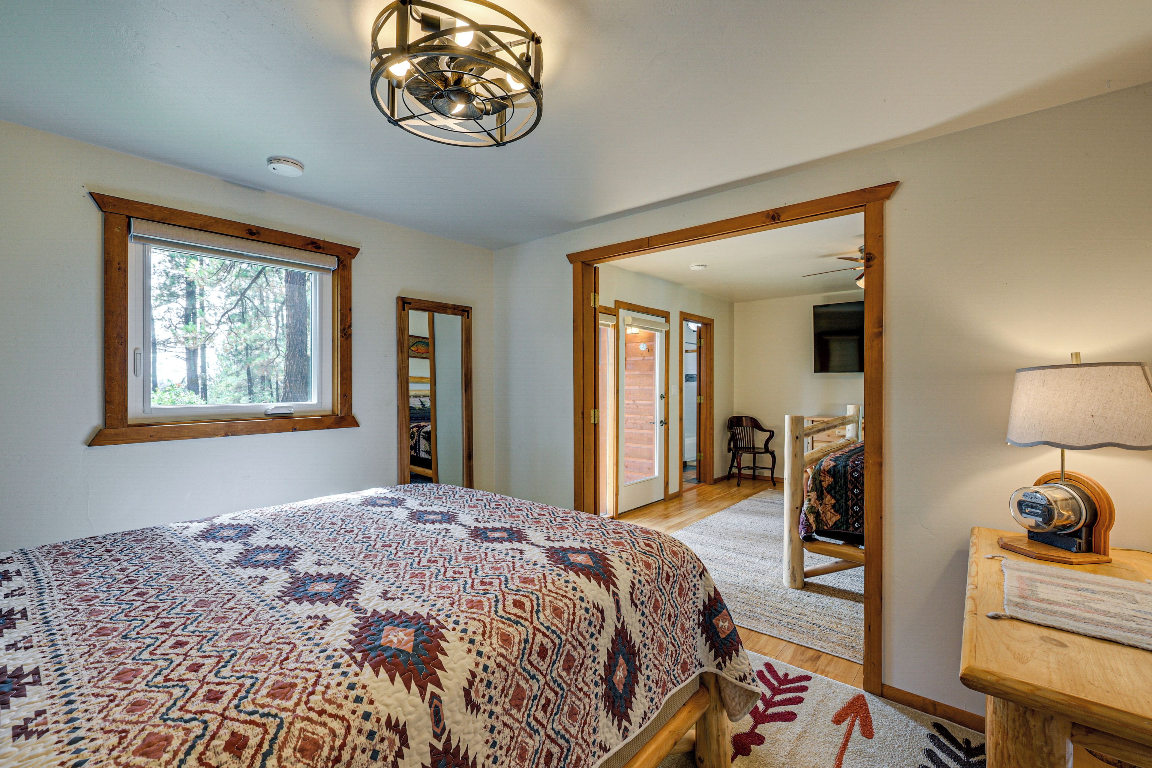 A bedroom with a large bed, a wooden nightstand, a mirror, and a ceiling fan.