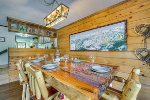 A wooden dining table set with plates, glasses, and cutlery, surrounded by wooden chairs. - Ski, Soak & Play at Littlefoot Cabin w/ Game Room (Pagosa Springs)