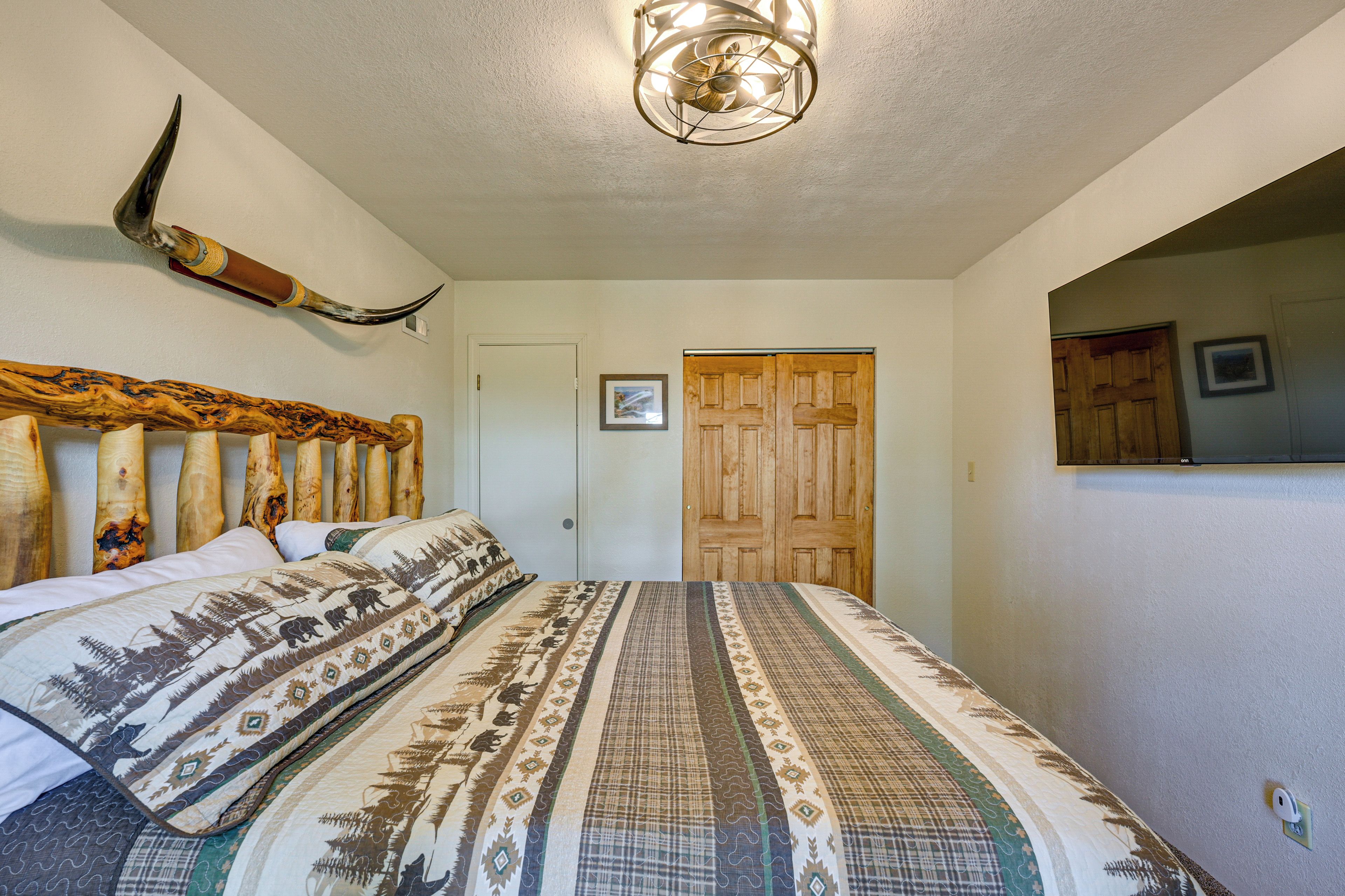 Une chambre à coucher avec un lit, une tête de lit en bois, un luminaire au plafond, une porte et un miroir sur le mur.