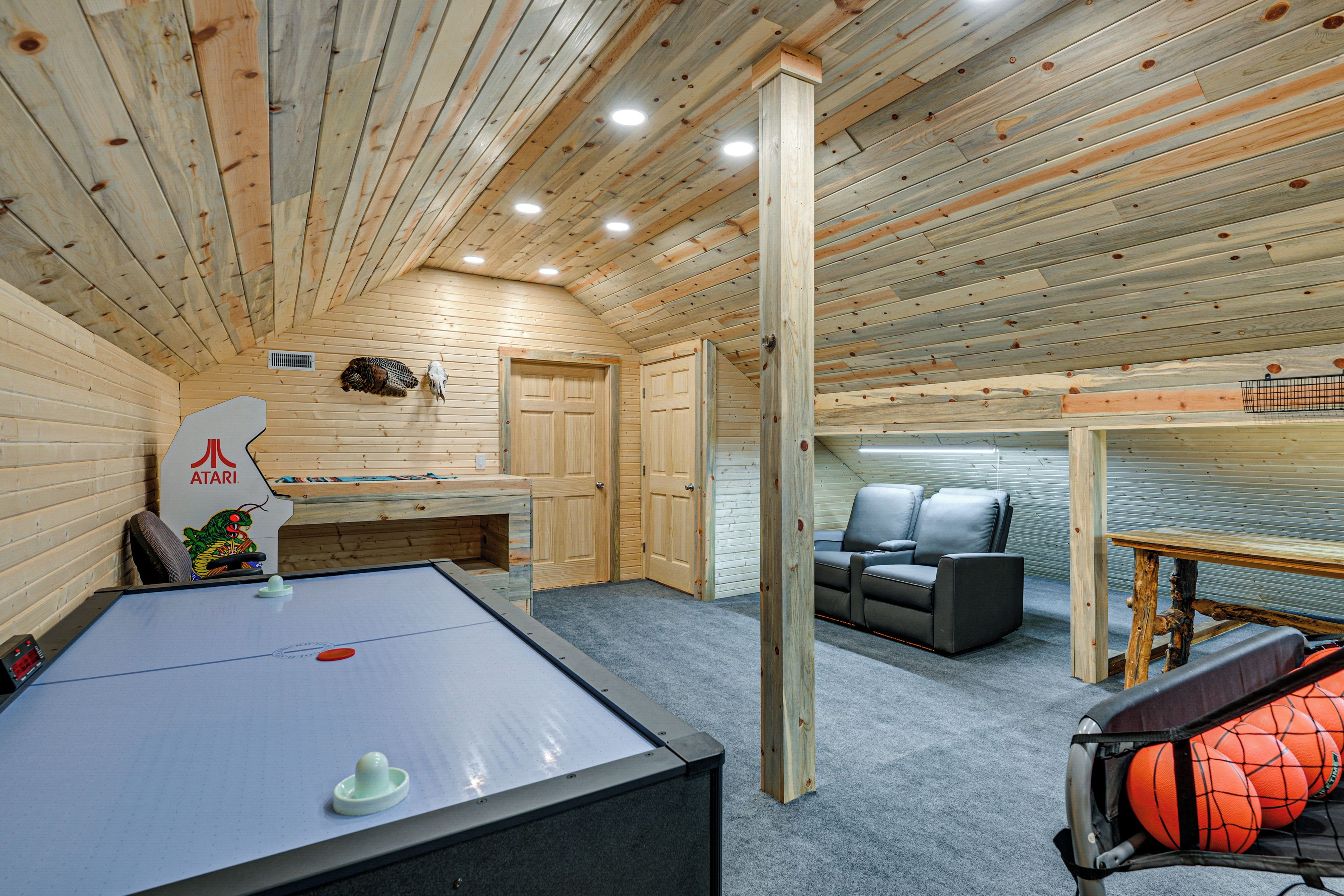 A room with a pool table, a sofa, and a basketball hoop.