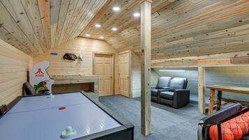 A room with a pool table, a sofa, and a basketball hoop.