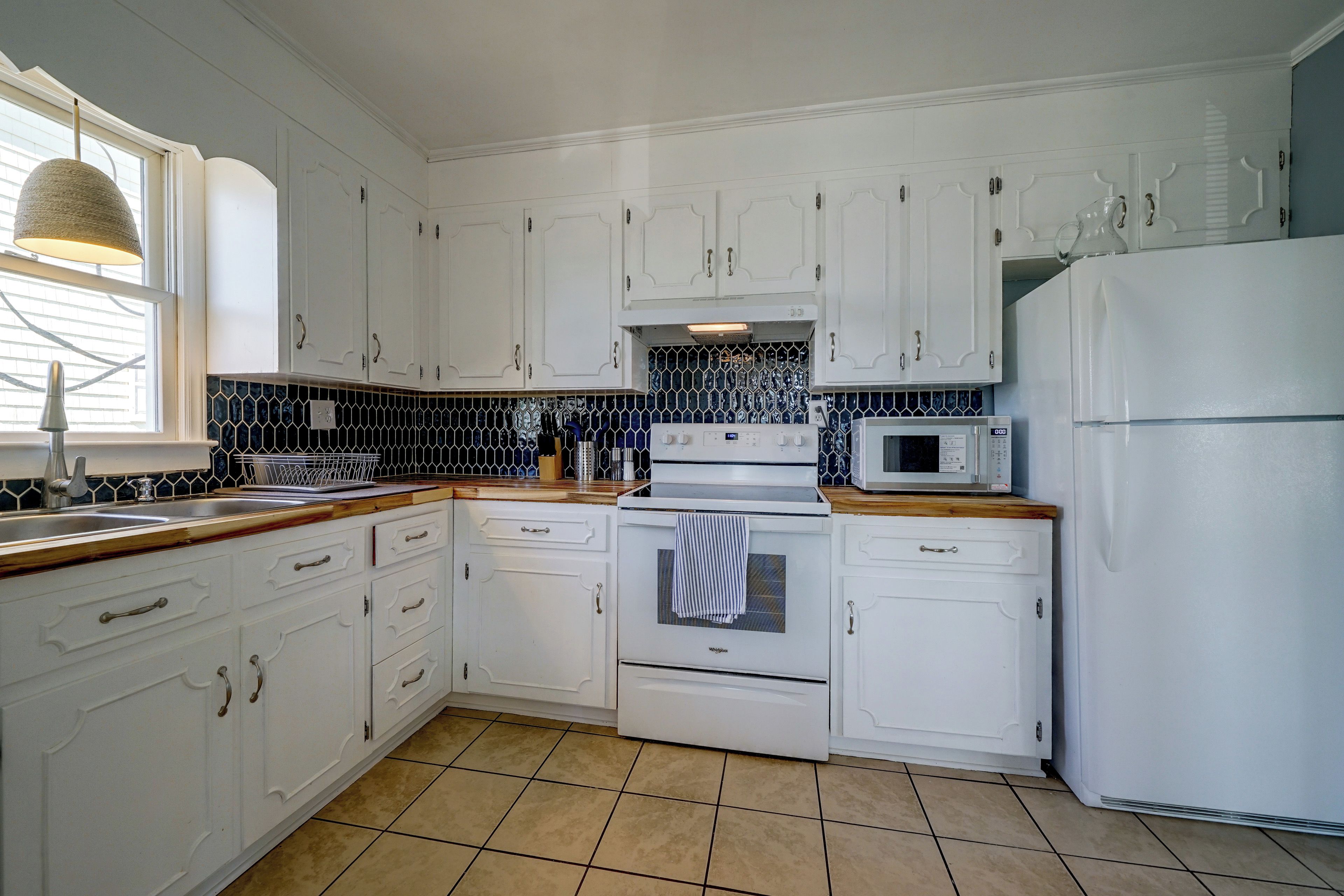 A kitchen with white cabinetry, a microwave, a stove, and a sink.
