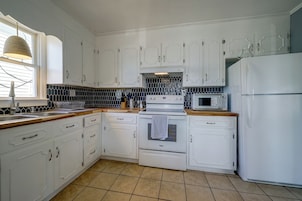 A kitchen with white cabinetry, a microwave, a stove, and a sink.