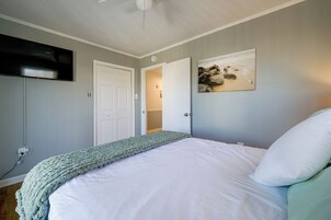 Un dormitorio con cama, televisor montado en la pared y un cuadro.