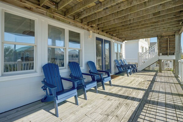 Un espacio de estar al aire libre con techo, sillas Adirondack y una terraza de madera.