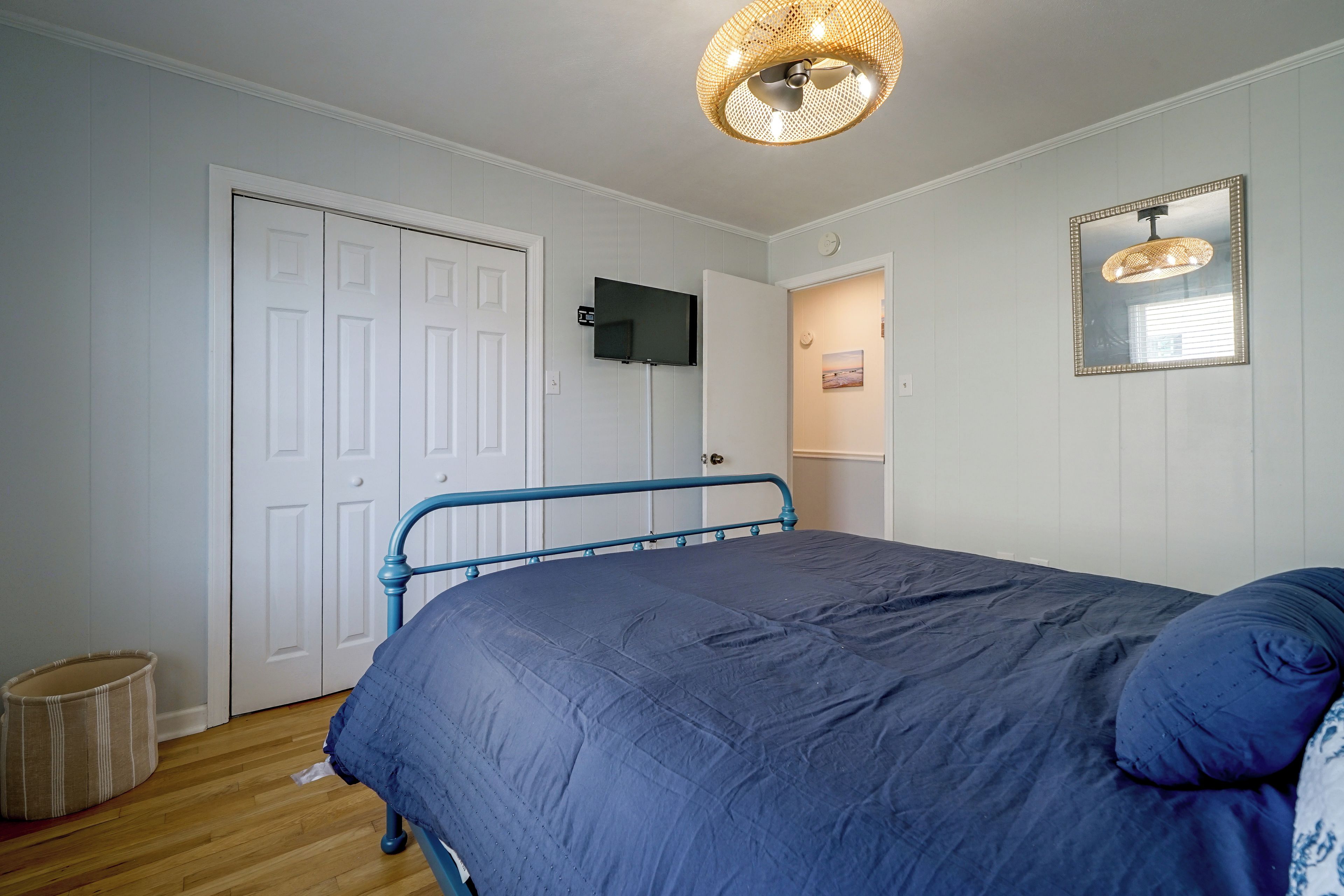 A bedroom with a bed, a television on the wall, and a door.