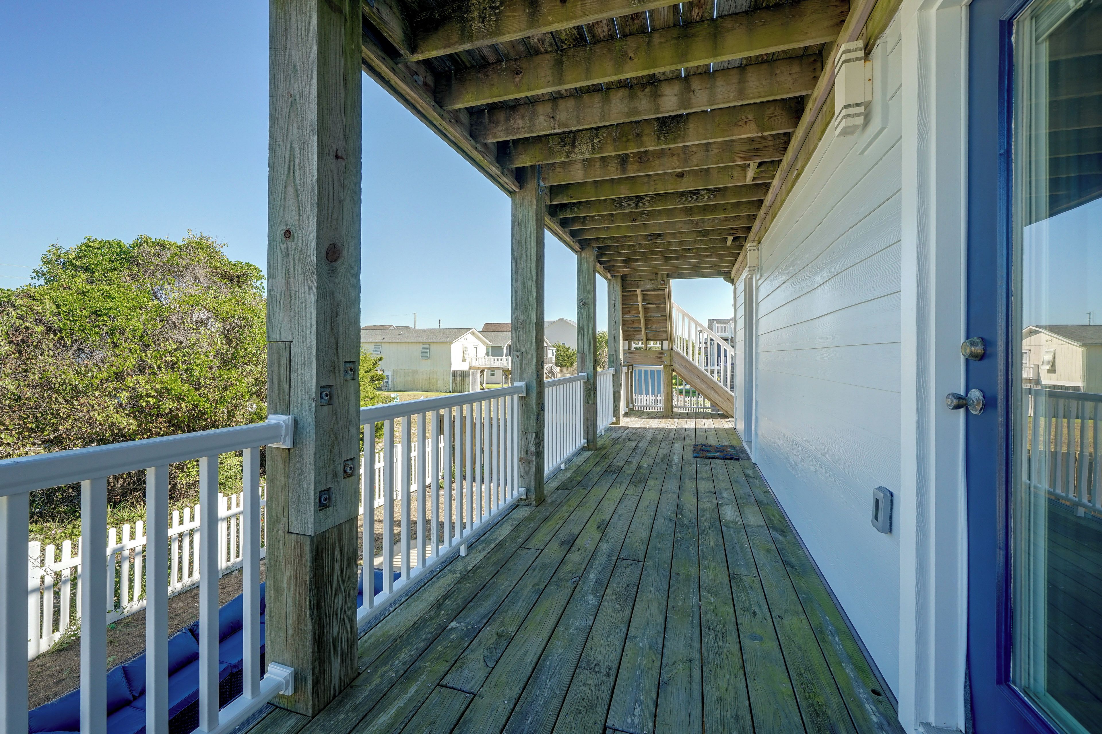 A wooden deck with a railing, a door, and a view of houses in the background.