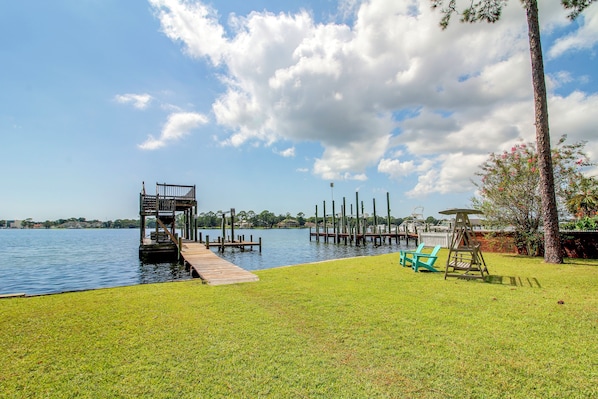 A lakeside property with a wooden dock, a grassy lawn, and a swing set. - Hot Tub & Dock Access! Bayfront Studio (Fort Walton Beach)